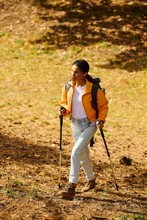 A young African American woman navigates a colorful forest trail, immersed in the beauty of autumn.