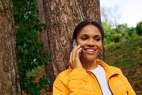 A young woman embraces the beauty of autumn while hiking in a lush forest, connected to nature.