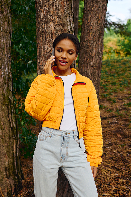 A young African American woman explores a colorful autumn forest, radiating joy and vitality during her hike.