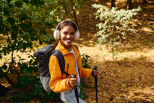 A spirited young woman embraces adventure while hiking in a colorful autumn forest, radiating joy.