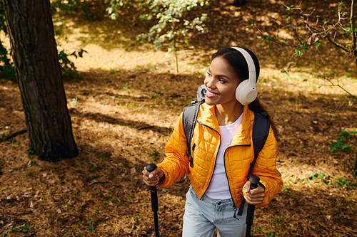 A joyful young woman explores a colorful autumn forest, listening to music while hiking with purpose.