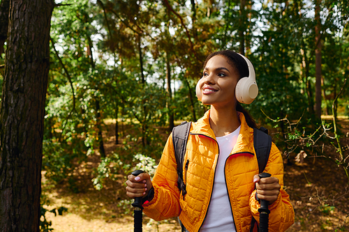 A young woman explores the vibrant autumn forest, enjoying her hike surrounded by nature beauty.