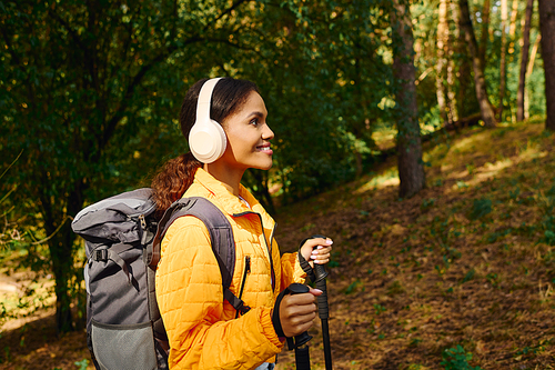 A young African American woman hikes through a colorful autumn forest, embodying an active lifestyle.