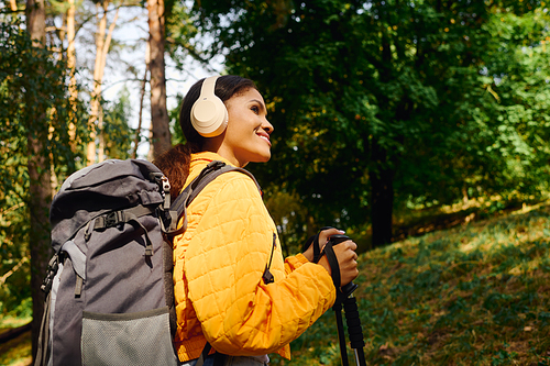 A young African American woman explores a vibrant autumn forest, embracing her adventurous spirit.