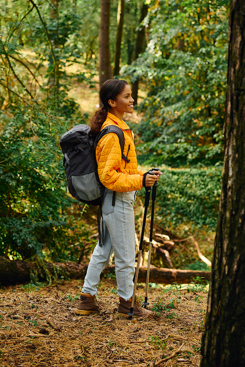 A young woman explores a colorful forest in autumn, embracing nature on her hiking journey.