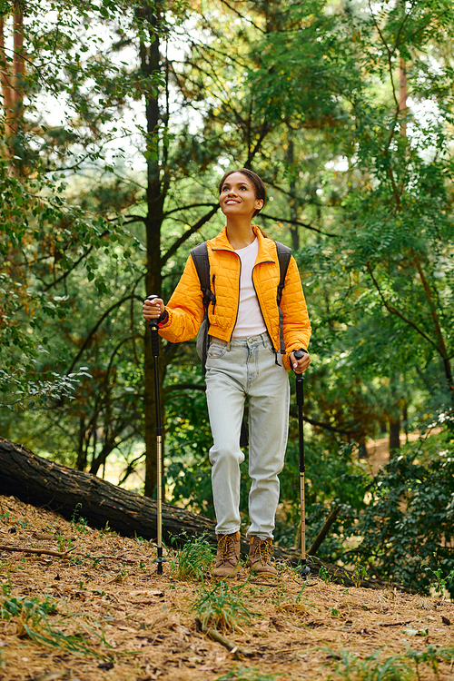 A young woman enjoys a hike in a colorful autumn forest, embracing nature with enthusiasm and joy.