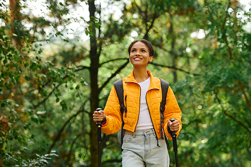 A young woman embraces the beauty of autumn while hiking through a lush forest, radiating joy and adventure.