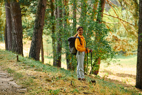 A young African American woman explores a beautiful forest, immersed in the autumn colors while hiking.