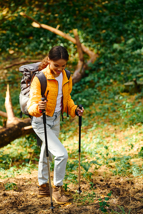 A young African American woman explores a colorful autumn forest, enjoying her hiking adventure.