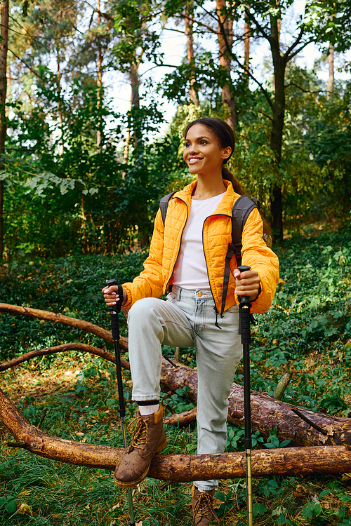 A young African American woman embraces adventure while hiking through a colorful autumn forest.