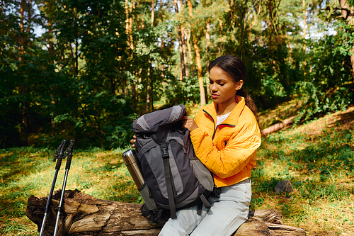 A young African American woman explores a colorful forest during autumn, embracing nature beauty and adventure.