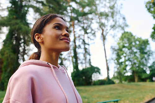 A young African American woman savors her hiking adventure in a beautiful autumn forest, embracing nature.