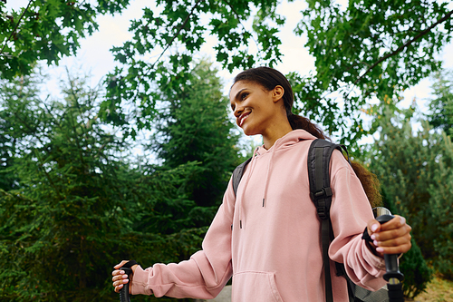 In a colorful autumn forest, a young woman enjoys her hike, connecting with nature and adventure.