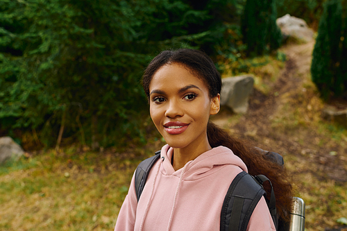 A young African American woman explores a colorful autumn forest, embracing the spirit of adventure outdoors.