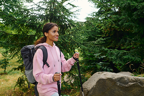 A young African American woman hikes through a colorful autumn forest, embracing adventure and nature.