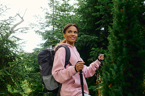 A young African American woman enjoys a hiking adventure through a colorful autumn forest