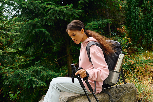 A young African American woman enjoys an autumn hike through the forest, surrounded by colorful foliage.