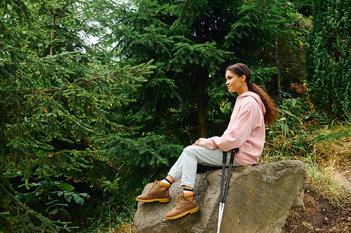 Amidst the stunning autumn foliage, a young woman rests on a rock, embracing nature during her hike.