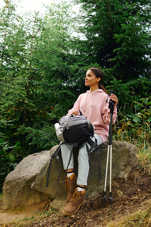 In the heart of autumn, a young woman takes a moment to enjoy nature while hiking in the lush forest.