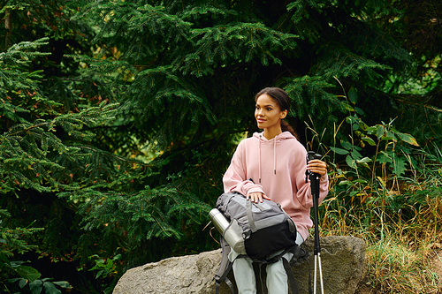 A young woman takes a moment to rest while hiking in a beautiful autumn forest surrounded by nature.