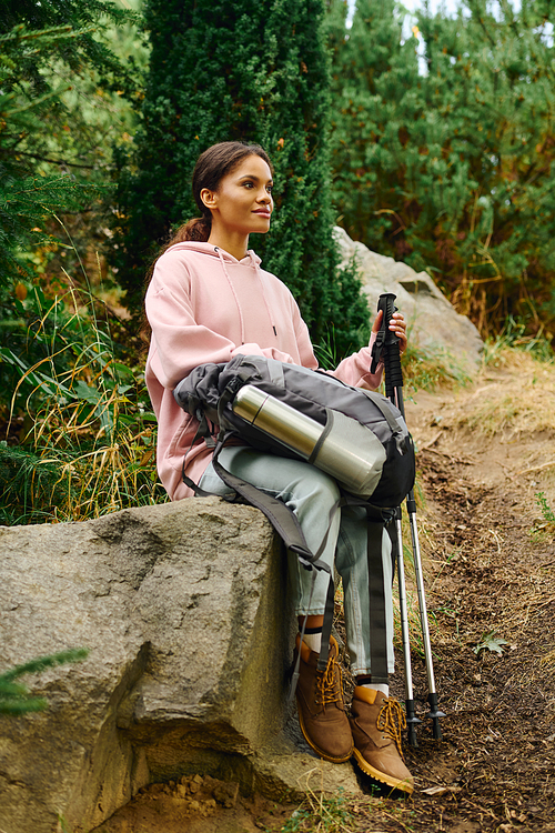 A young woman embraces the beauty of autumn as she hikes through a lush forest, soaking in the adventure.