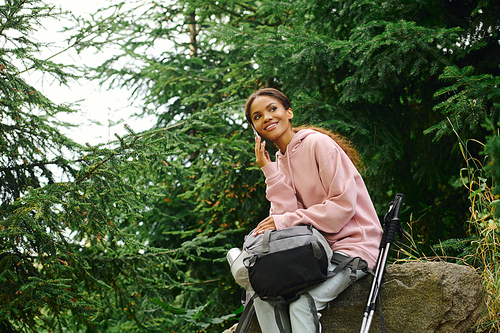 In a colorful autumn forest, a young woman takes a moment to enjoy her hiking adventure while resting.