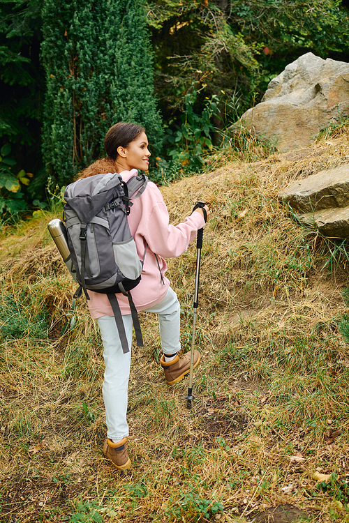 A young African American woman hikes through a colorful autumn forest, embracing nature and adventure.