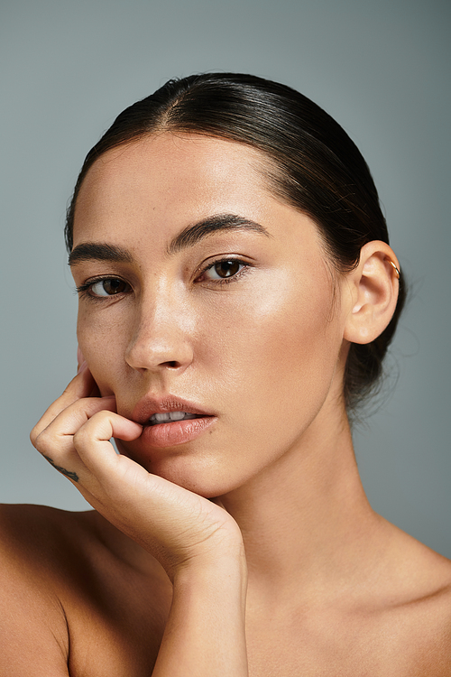 A woman poses gracefully, displaying a calm expression with soft lighting highlighting her features.