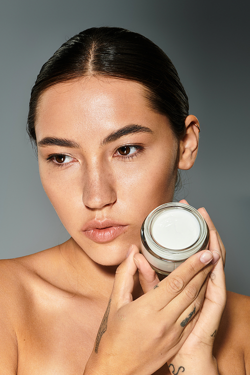 A woman highlights her skincare routine, holding a natural product with confidence.