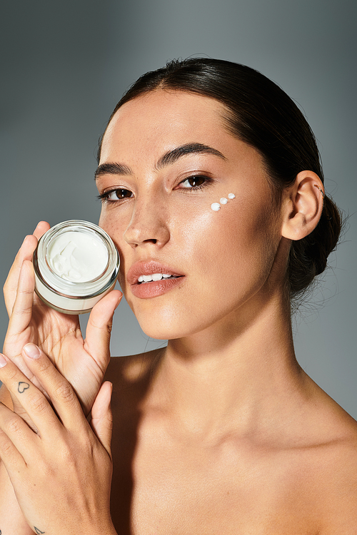 The woman holds a jar of skincare while demonstrating her beauty routine with confidence.