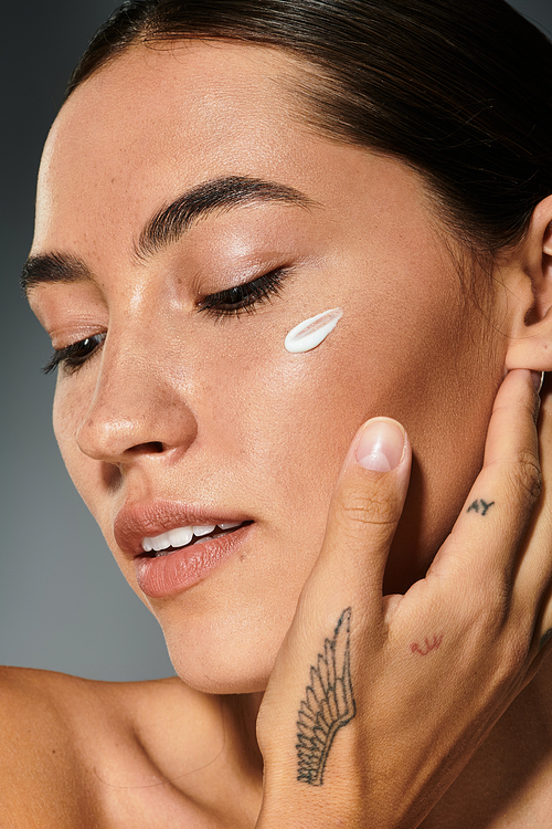 A woman gently touches her face while applying a nourishing cream during the afternoon.