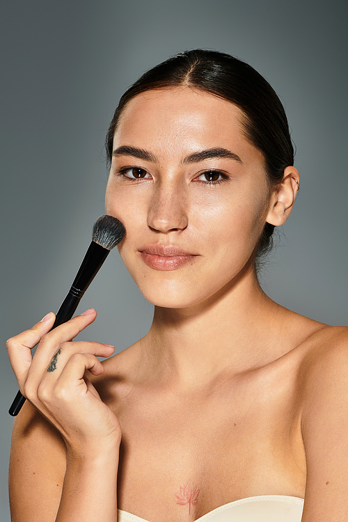 A woman enjoys applying makeup, enhancing her natural beauty with a brush in the studio light.