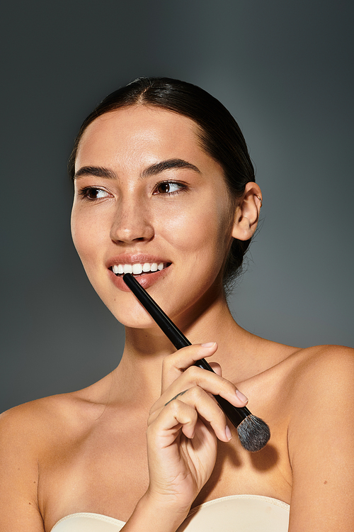 A woman enjoys applying makeup with a brush, radiating joy and confidence in a serene atmosphere.