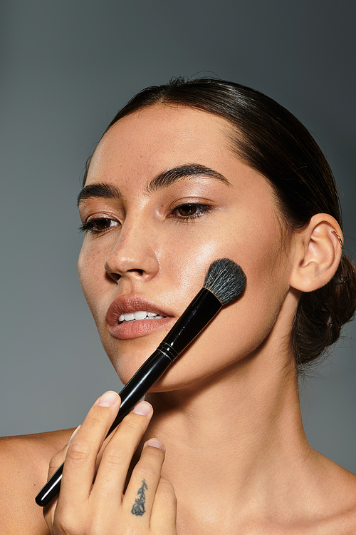 A beautiful woman enhances her features with a makeup brush in a serene environment.