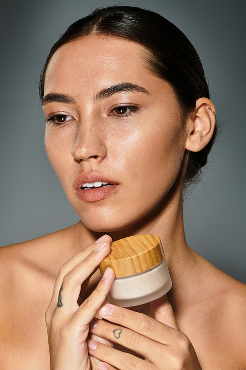 A graceful woman holds a skincare jar, her expression reflecting beauty and confidence.