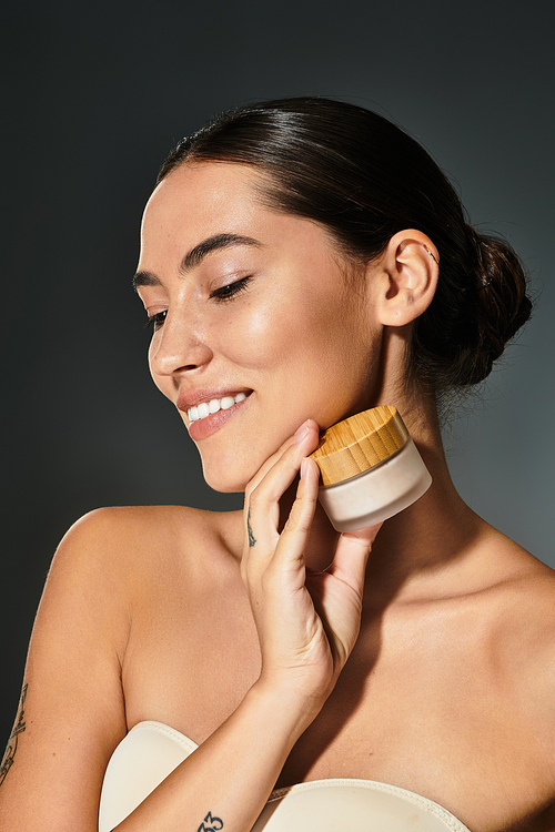 The woman holds a jar of cream close to her face, radiating joy and confidence.