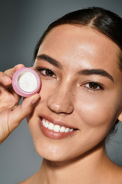 The woman demonstrates a skincare item, highlighting her natural beauty and glowing complexion.