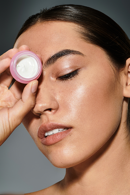 A beautiful woman gently applies moisturizer to her skin, embracing a moment of self care.