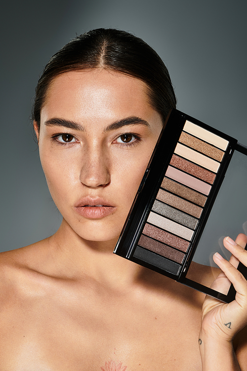 The beautiful woman, with a natural look, highlights a palette of shimmering eyeshadow shades.