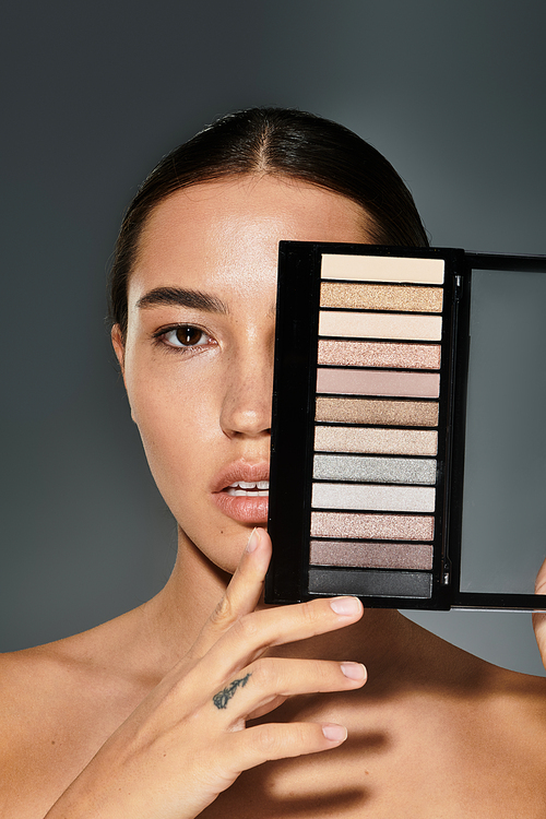 The beautiful woman holds an eyeshadow palette while highlighting her artistic side.