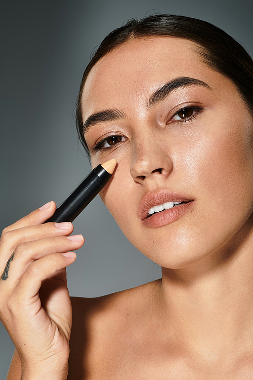 The woman applies concealer to accentuate her features, showcasing a serene expression.