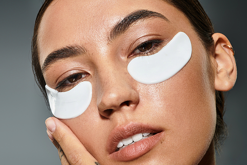 Relaxation and self care unite as a woman applies under eye patches for rejuvenation.