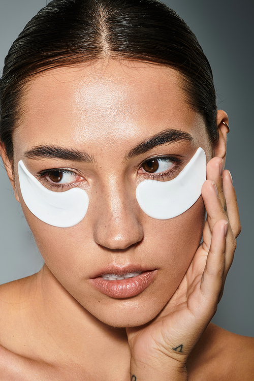 A beautiful woman gently applies under eye patches while preparing for a skincare ritual.