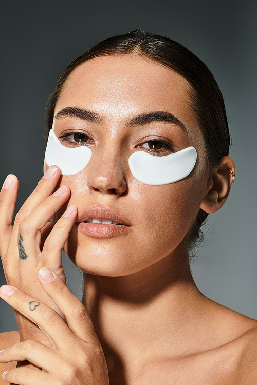 A woman uses eye patches, highlighting her natural beauty and calm demeanor.