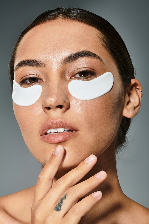 A stunning woman refreshes her look with skincare patches on her face, exuding confidence and grace.