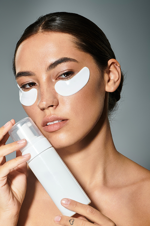 A radiant woman applies skincare near a soft backdrop while focusing on her beauty routine.