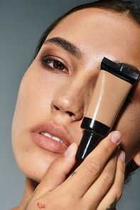 The woman gracefully applies foundation to her face with a confident expression.