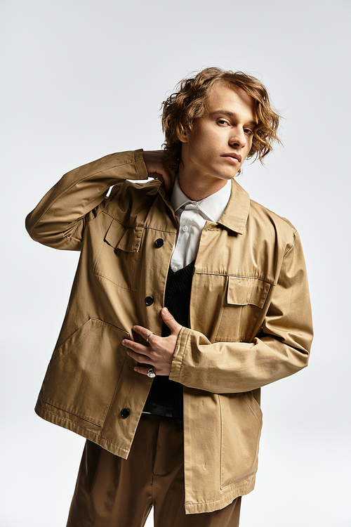 A handsome young man dresses elegantly for autumn, displaying wavy hair in a sophisticated studio backdrop.