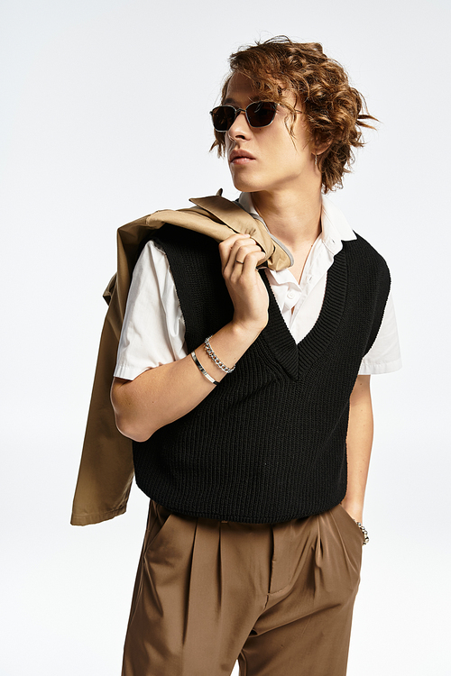 A handsome young man with wavy hair exhibits autumn-inspired fashion in a chic studio space.