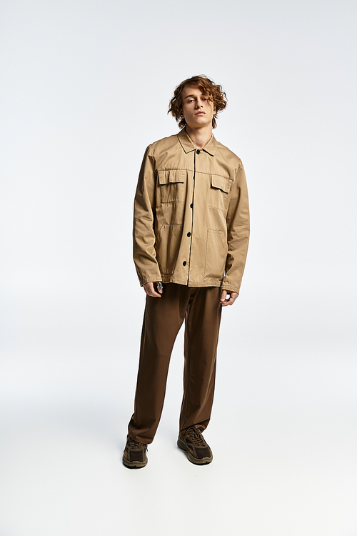 A handsome young man with wavy hair models a chic autumn outfit in a contemporary studio space.